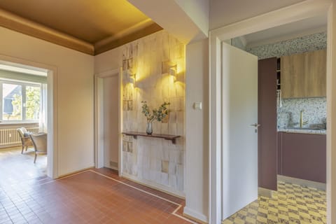 Charming hallway leading to the well-equipped kitchen. Elegant lighting and stylish decor create a warm and inviting ambiance throughout the apartment.