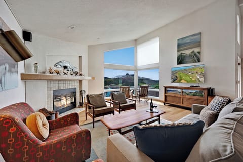 Inviting living room with a wood burning fireplace and large TV. View the sunset from the corner window.