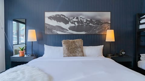 Unwind into crisp linens beneath calming alpine-inspired artwork.