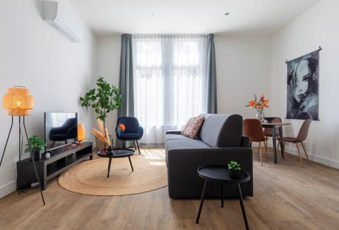 A contemporary living area with a plush sofa, chic chairs, sleek round tables, a TV unit, and natural accents, all enhanced by warm hues and lush greenery, seamlessly linking to the dining space.
Apart-Hotel – close to the university, city center, Efteling & Safaripark Beekse Bergen. Equipped with a new kitchen and a luxury bathroom.