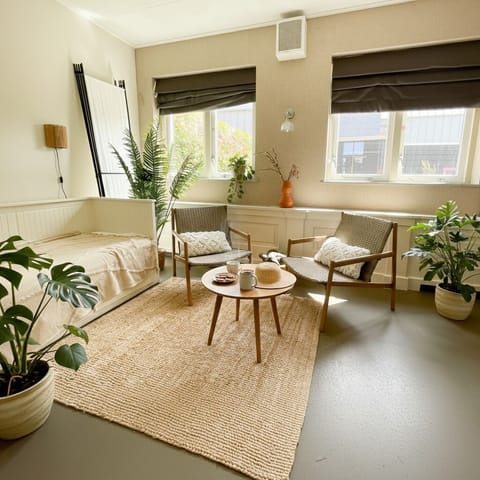 Bright coastal room with natural tones, comfy seating, and lush indoor plants — perfect for a peaceful stay near the beach in Zoutelande.