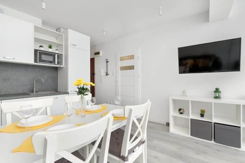 A modern kitchen with sleek white cabinets, a grey countertop, and a bowl of oranges for a splash of color. The space is clean and functional.