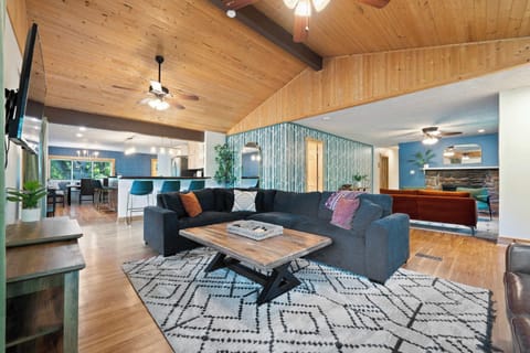 Relax in this open-concept living area with vaulted wood ceilings, plush seating, and modern rustic charm. Perfect for movie nights, game time, or unwinding by the fire, this inviting space is designed for friends and family to connect and enjoy.