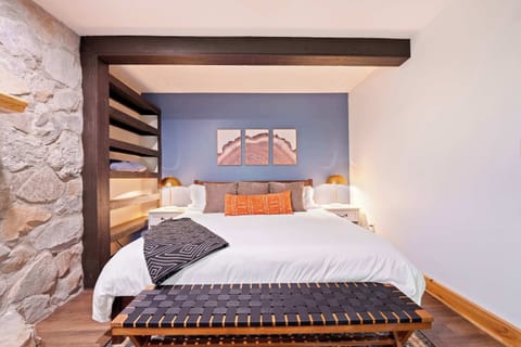 This stylish king bedroom blends rustic charm with modern comfort. Cozy up with soft linens, warm lighting, and built-in shelving for convenience. The perfect space to relax after a day of exploring.