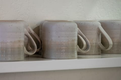 - Handmade style ceramic mugs add charm to your morning routine or evening tea - Neatly stacked on floating shelves for easy access during your stay - Each one has a rustic touch that complements the cozy cabin aesthetic