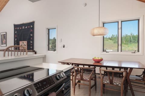 - Charming dining area with wooden chairs and mid century table set for meals - Soft pendant lighting and wall art elevate the clean, cozy cabin vibe - Conveniently located next to the stove for easy mealtime flow and comfort