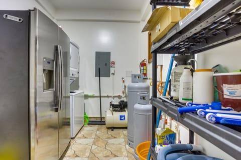 Pool utility room with apartment laundry and extra refrigerator with ice and water.