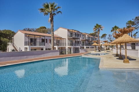 Relax and unwind by the expansive swimming pool, featuring comfortable loungers and surrounded by palm trees. Ideal for soaking up the sun and enjoying a refreshing dip.