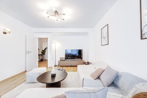 Experience the welcoming ambiance of our living room from another angle, highlighting the ample seating space and modern entertainment setup.