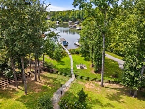 A picturesque lakefront property featuring a serene dock, lush greenery, and a cozy fire pit, perfect for relaxation and outdoor enjoyment.