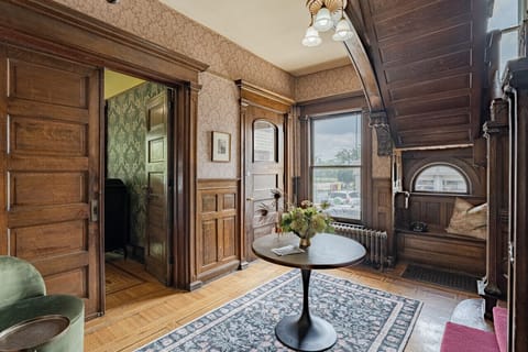 Another view from the welcoming foyer, adorned by wallpaper and original woodwork