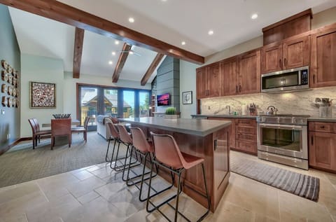 Enjoy cooking and dining in this spacious kitchen featuring modern appliances, a large island with seating, and exposed beam ceilings.