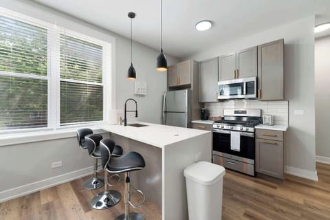 A bright, modern kitchen featuring stainless-steel appliances, sleek cabinetry, and a spacious island perfect for cooking or casual dining. Fully equipped and flooded with natural light—ideal for morning coffee or preparing your favorite meals.