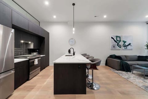 “Contemporary kitchen featuring white cabinetry, a central island, and stainless-steel appliances.