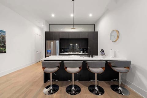 “Contemporary kitchen featuring white cabinetry, a central island, and stainless-steel appliances.