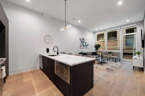 “Contemporary kitchen featuring white cabinetry, a central island, and stainless-steel appliances.