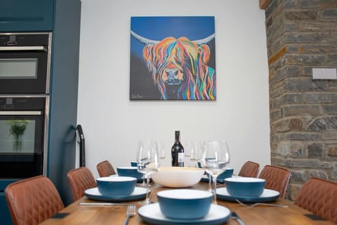 Dining table laid for dinner and large piece of art on  the wall