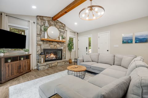 Enjoy the cozy living room, open to the kitchen and dining room, featuring a warm gas fireplace and a plush sectional sofa—perfect for relaxing! 
