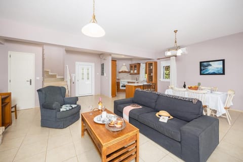 Open-plan living room with sofa, dining area, kitchen, ornamental fireplace, A/C, WiFi internet, and satellite TV