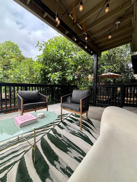 Back covered deck with lounge chairs and string lights. 
