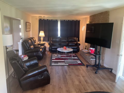 Living room with leather sofa, loveseat, recliner, 65" Roku TV w/spectrum.