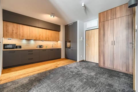 Modern kitchen area with grey cabinets, wooden countertops, and bright lighting.
