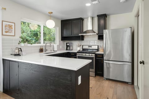 Enjoy our fully stocked kitchen with sleek black cabinets and pristine white quartz countertops that offer a modern, stylish space where you can easily prepare meals or grab a quick snack, with everything from pots and pans to handy appliances within reach. 
