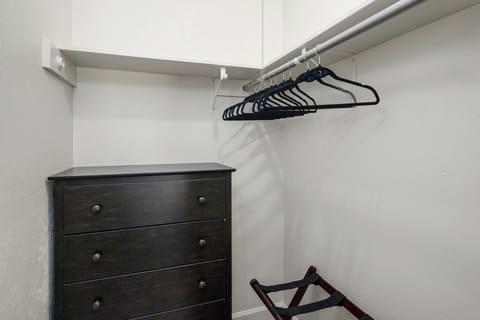 The second bedroom features a spacious walk-in closet equipped with a dresser, hangers, laundry hamper, and a convenient luggage rack for optimal storage and organization.