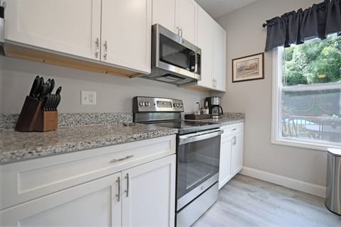 Kitchen fully stocked with all the cooking essentials, stainless steel appliances, granite countertops, island seating.