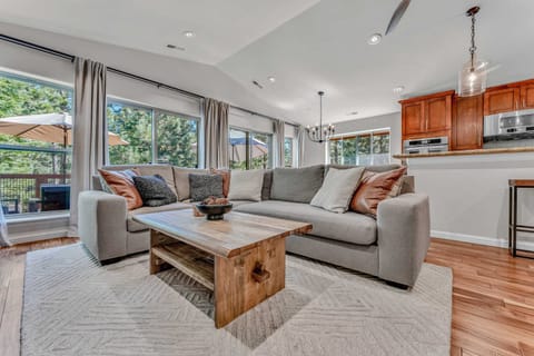 Living Room: L-shaped couch, 65” Smart TV, connected to kitchen/dining room, opens to patio