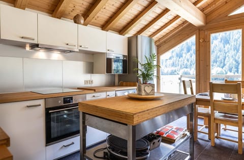 This fully equipped kitchen combines modern appliances with rustic wooden finishes, providing a beautiful and functional space for meal preparation. Large windows offer scenic views to enjoy while cooking.