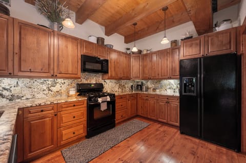 - Spacious kitchen with granite countertops and storage - Black appliances and wood cabinets for modern comfort - Fully equipped for cooking, baking and family meals