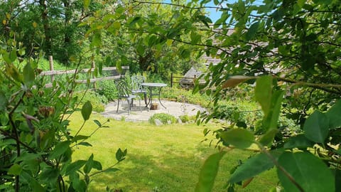 Bistro table and chairs on a small patio area surrounded with a lawn and mature planting