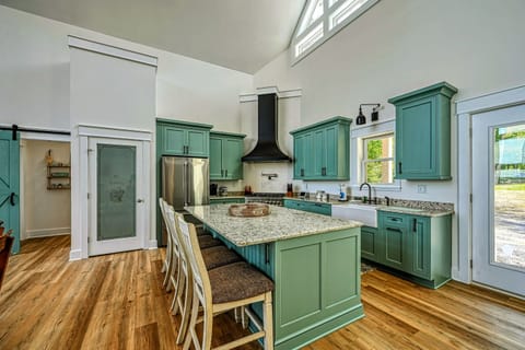 Spacious and modern kitchen with a large island, stylish green cabinetry, and plenty of natural light, perfect for cooking and entertaining