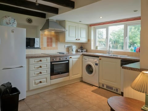 Kitchen in Y Bwthyn with units, cooker, washing machine, fridge, microwave and window