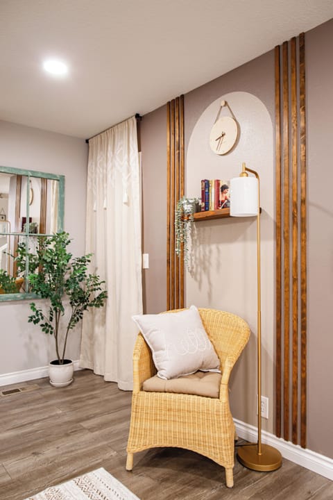 Cozy corner with rattan chair, rustic frame window mirror and greenery