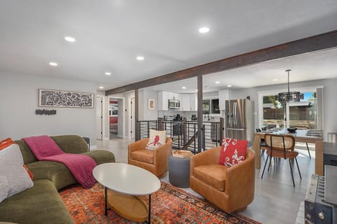 A vibrant main living room with bold colors and chic decor, seamlessly flowing into the open dining and kitchen areas for a spacious and welcoming feel.