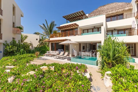 A stunning beachfront retreat featuring lush landscaping, a private pool, and direct access to the sandy shores.