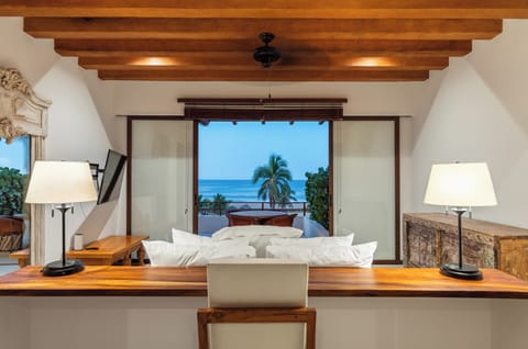 Wake up to palm-framed ocean views in this elegant bedroom, complete with a private desk space and sliding doors that open to a breezy terrace.