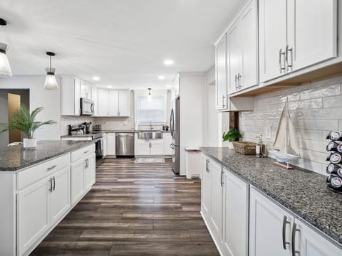 Fully stocked kitchen with sleek white cabinets, granite countertops, and modern lighting. 🌱🧑‍🍳