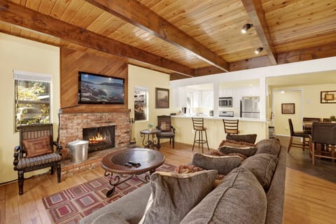 Cozy mountain living room with a stone fireplace, comfy seating, and smart TV—perfect for relaxing evenings, movie nights, and warm cabin vibes after outdoor adventures.