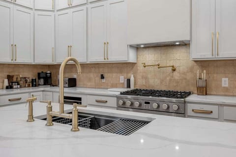 Astonishing kitchen with white cabinets, stainless steel appliances, a large island, and elegant lighting perfect for cooking and entertaining.