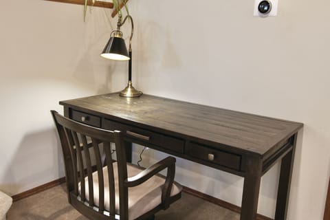 Features a large wooden desk, comfortable chair, laptop stand, and task lamp