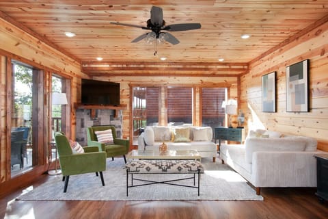 Bright and stylish cabin living room with cozy seating, fireplace, and woodland views