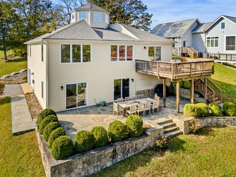 Beautiful lakefront home with a spacious stone patio and elevated deck, perfect for outdoor dining and relaxation