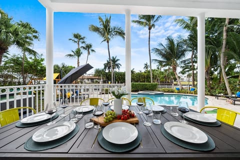 Covered patio with dining table overlooking the pool, perfect for al fresco meals and family gatherings. #OutdoorDining #LuxuryVacation #PoolsideLiving
