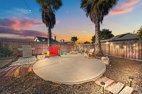 Backyard with firepit, play area, BBQ, loungers, palm trees, and studio.