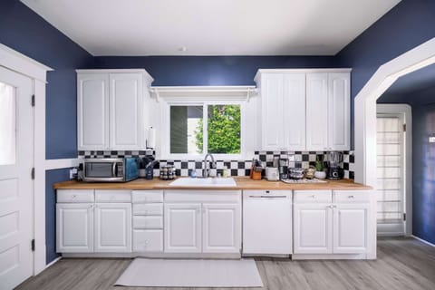 Bright kitchen with white cabinets, wood countertops, and tile accents.