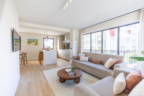 Relax in a spacious, sun-drenched living room with floor-to-ceiling windows, modern furnishings, and access to your private balcony - ideal for a luxury beachside stay.