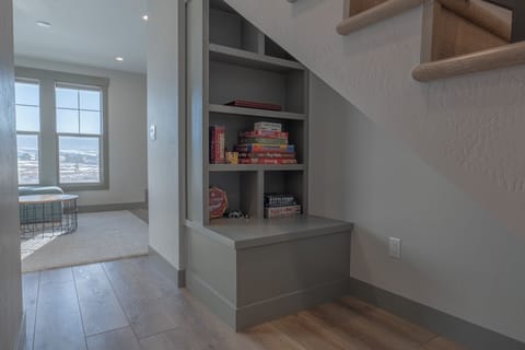 Cozy under-stair book nook stocked with games for family entertainment.